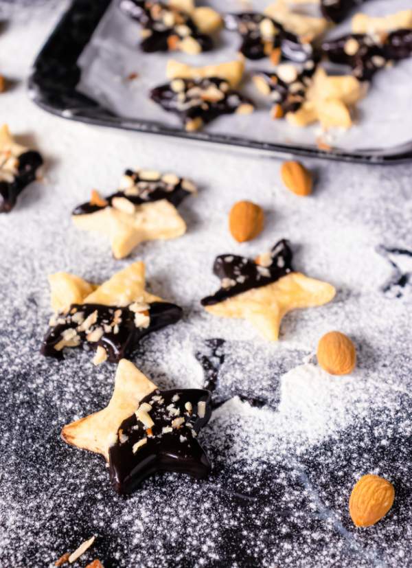 Holiday Shortbread Star Shaped Cookies arranged on a black table with sugar powder and almonds