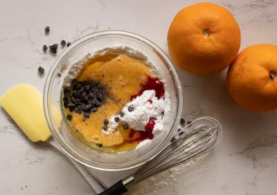 wet ingredients added to the dry with oranges and spatulas beside