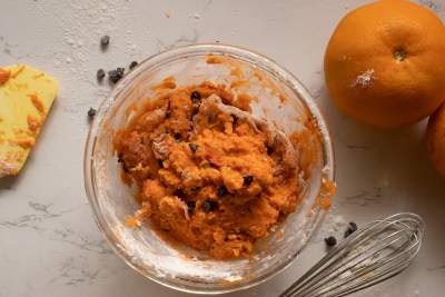 orange chocolate chip cookie dough kept in a bowl with oranges beside